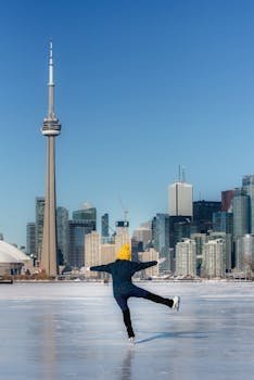 Woman ice skating on frozen lake in front of Toronto skyline and CN Tower during winter.