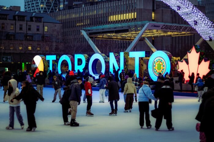 A lively ice skating scene with people enjoying winter at Toronto's illuminated sign.